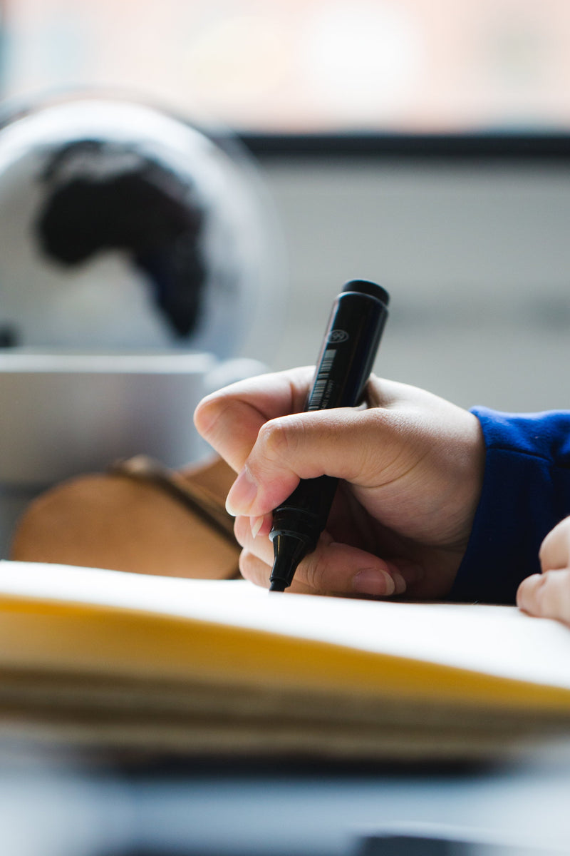 a hand with a marker journaling in a book